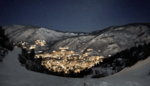 The city of Aspen glows at the base of Aspen Mountain, as seen from the top of the Little Nell ski run on January 9, 2022. A new documentary, “The Paradise Paradox,” explores the complex dynamics of mental health in mountain towns that are known for natural beauty and lively celebrations.